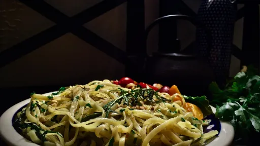 Wegańskie tagliatelle z ziołami, pomidorami i cytryną na talerzu. Styl vegestyl, zdrowe jedzenie.