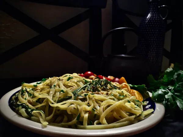 Wegańskie tagliatelle z ziołami, pomidorami i cytryną na talerzu. Styl vegestyl, zdrowe jedzenie.